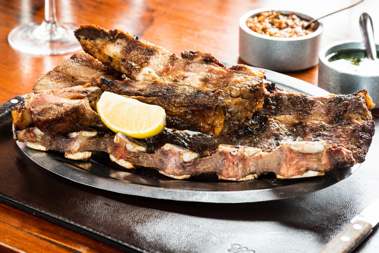 Costillar asado servido con limón y salsas