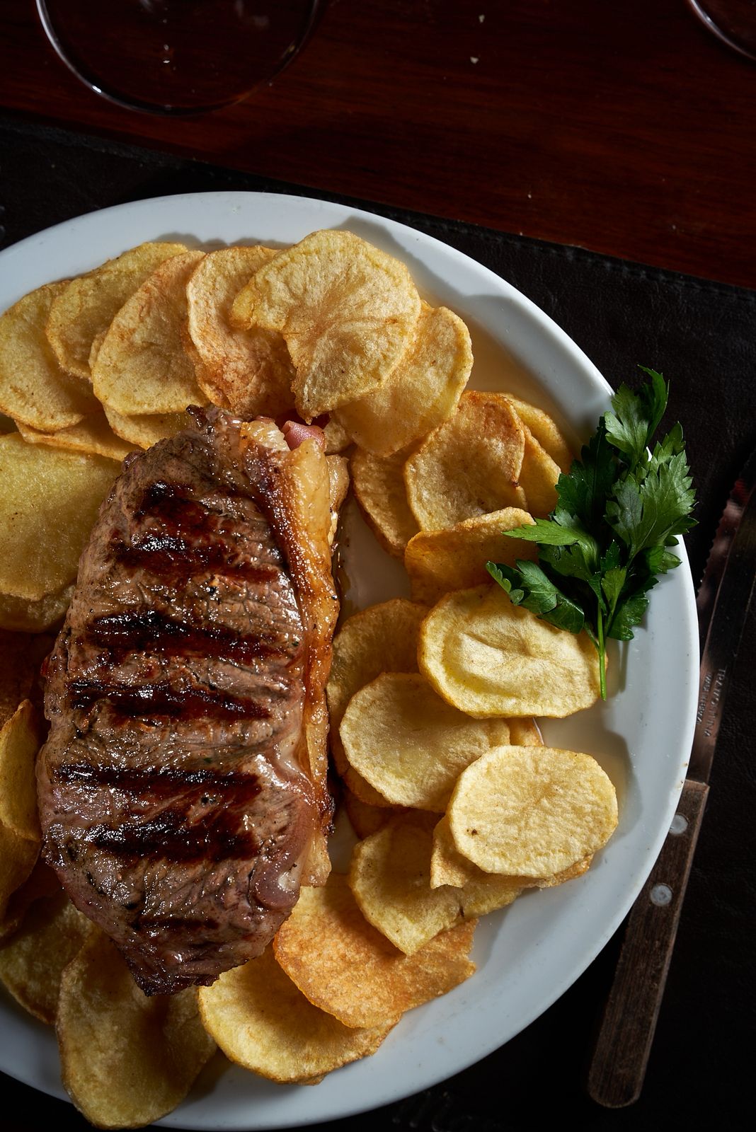 Bife de chorizo con papas españolas y una copa de vino